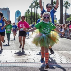 Girls on the Run participant high fives running buddy at 5K